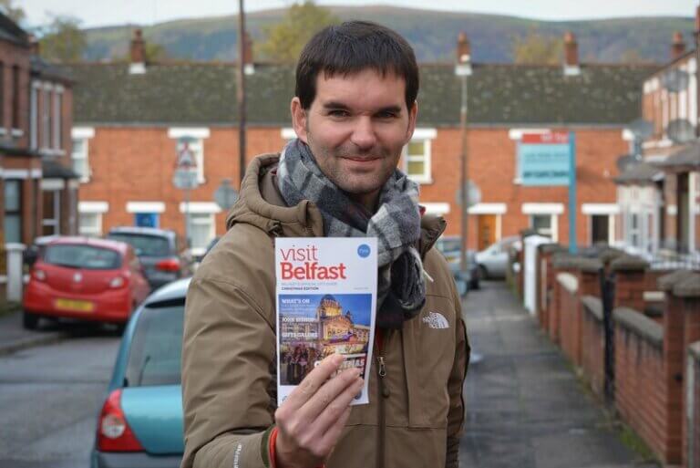 Man holding brochure saying 'visit Belfast'